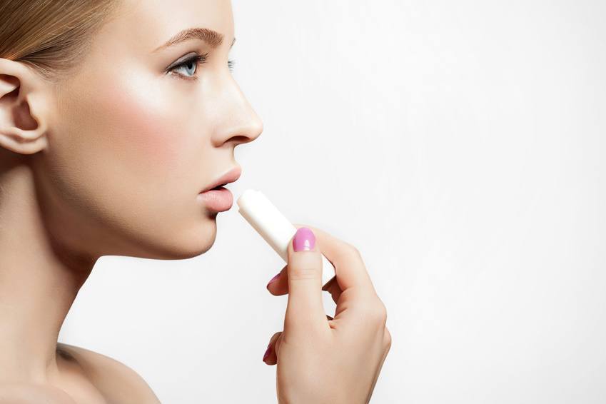 Woman With Healthy Skin Applying A Protective Lip Balm N A White Background